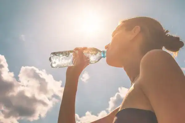Hydration: The Secret Ingredient for a Toned Stomach and Enhanced Fitness 3 Image of woman drinking water to hydrate Worthing after run.