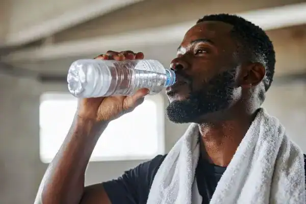 Hydration: The Secret Ingredient for a Toned Stomach and Enhanced Fitness 1 Image of man drinking water to improve hydration Worthing after work out.